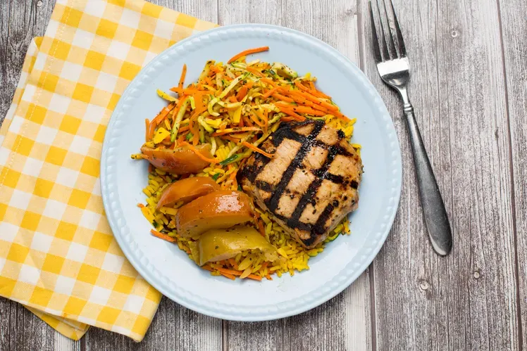 grilled pork chops with roasted apples and yellow rice, signifying meat-based home-cooked meal prep delivery